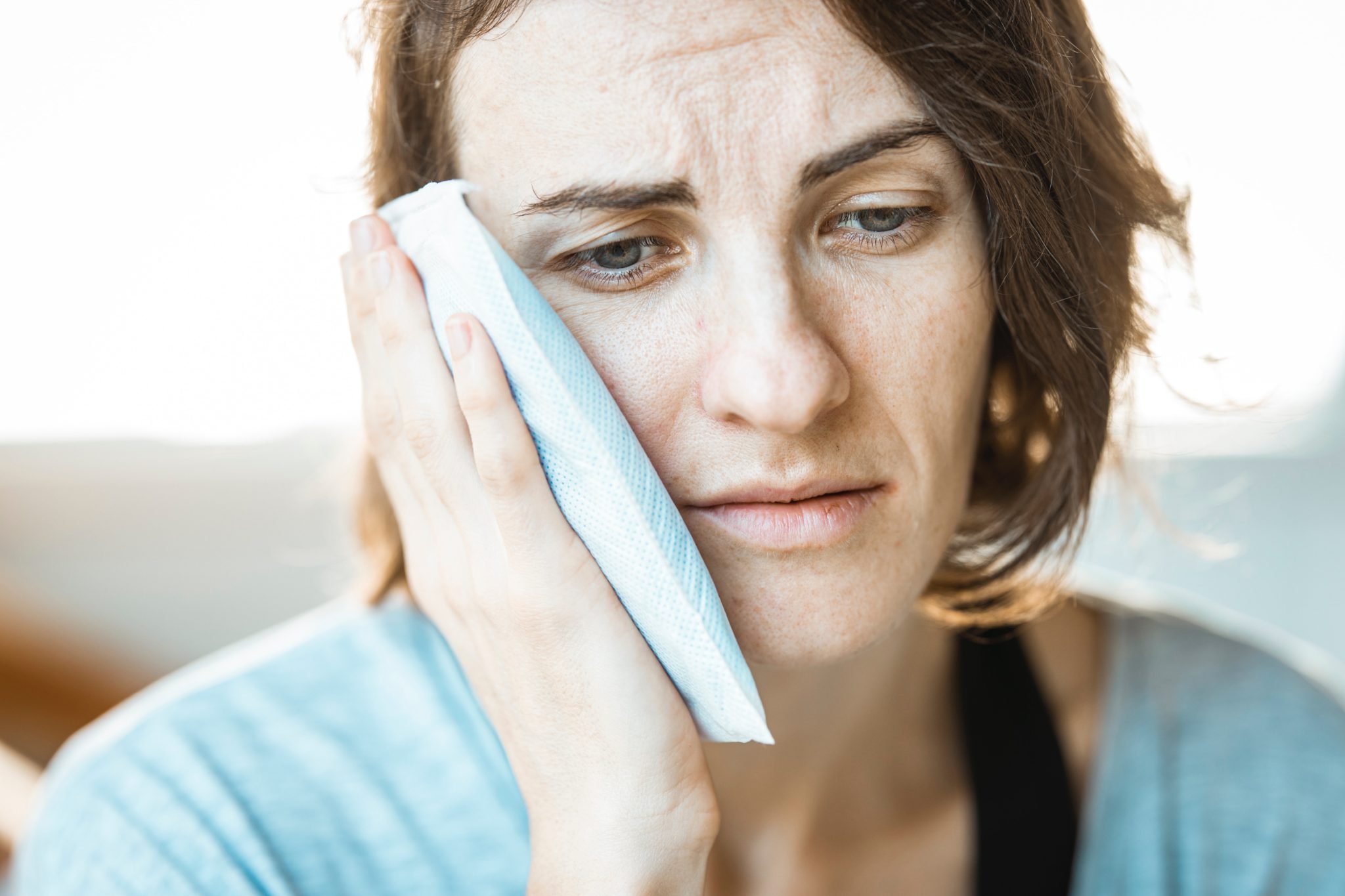 woman holding a tissue next to the face because of a headache caused by bruxing
