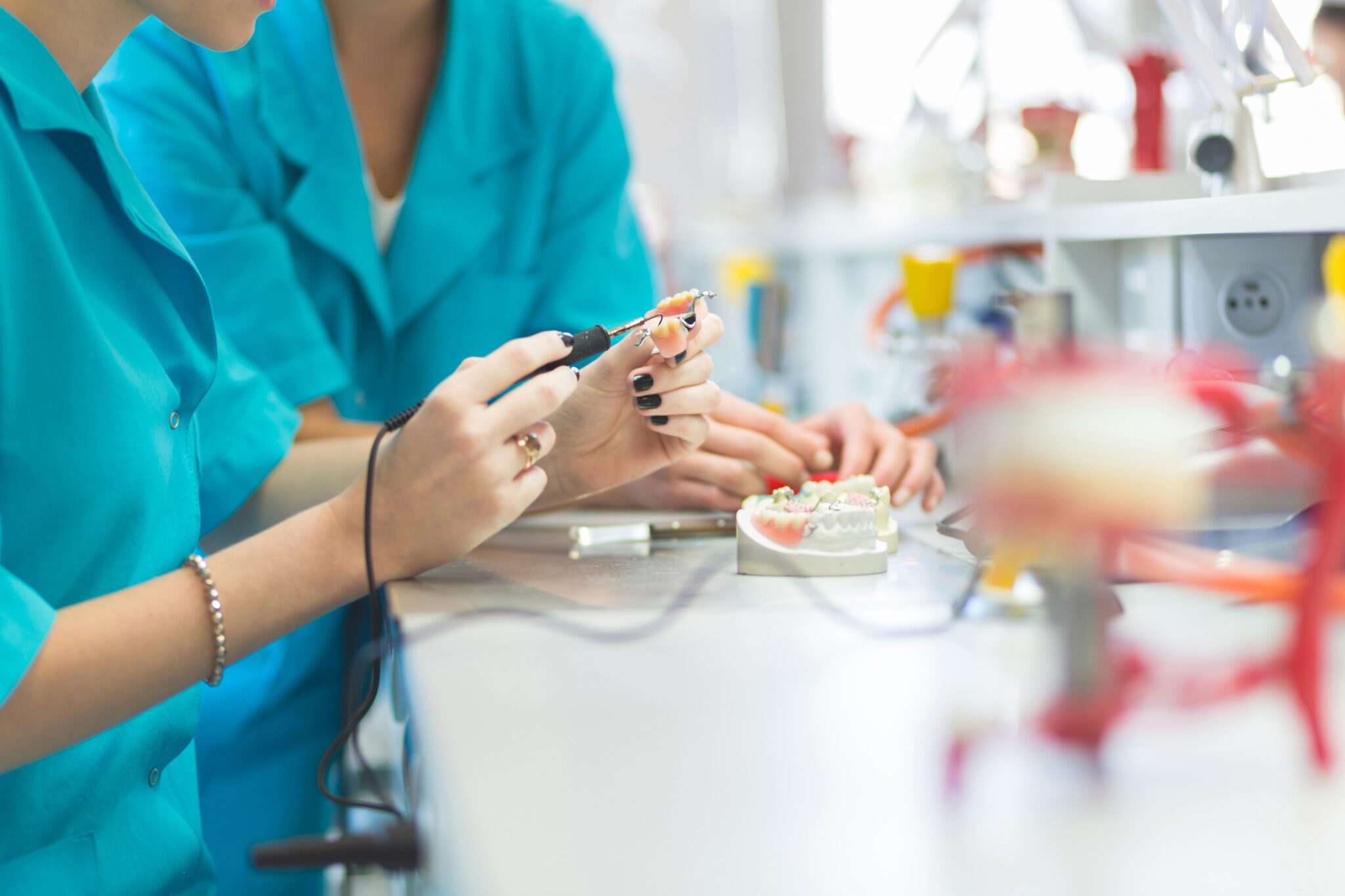 Women in a prosthodontic lab, learning prosthetic dentistry, close up of hands, unrecognizable person.